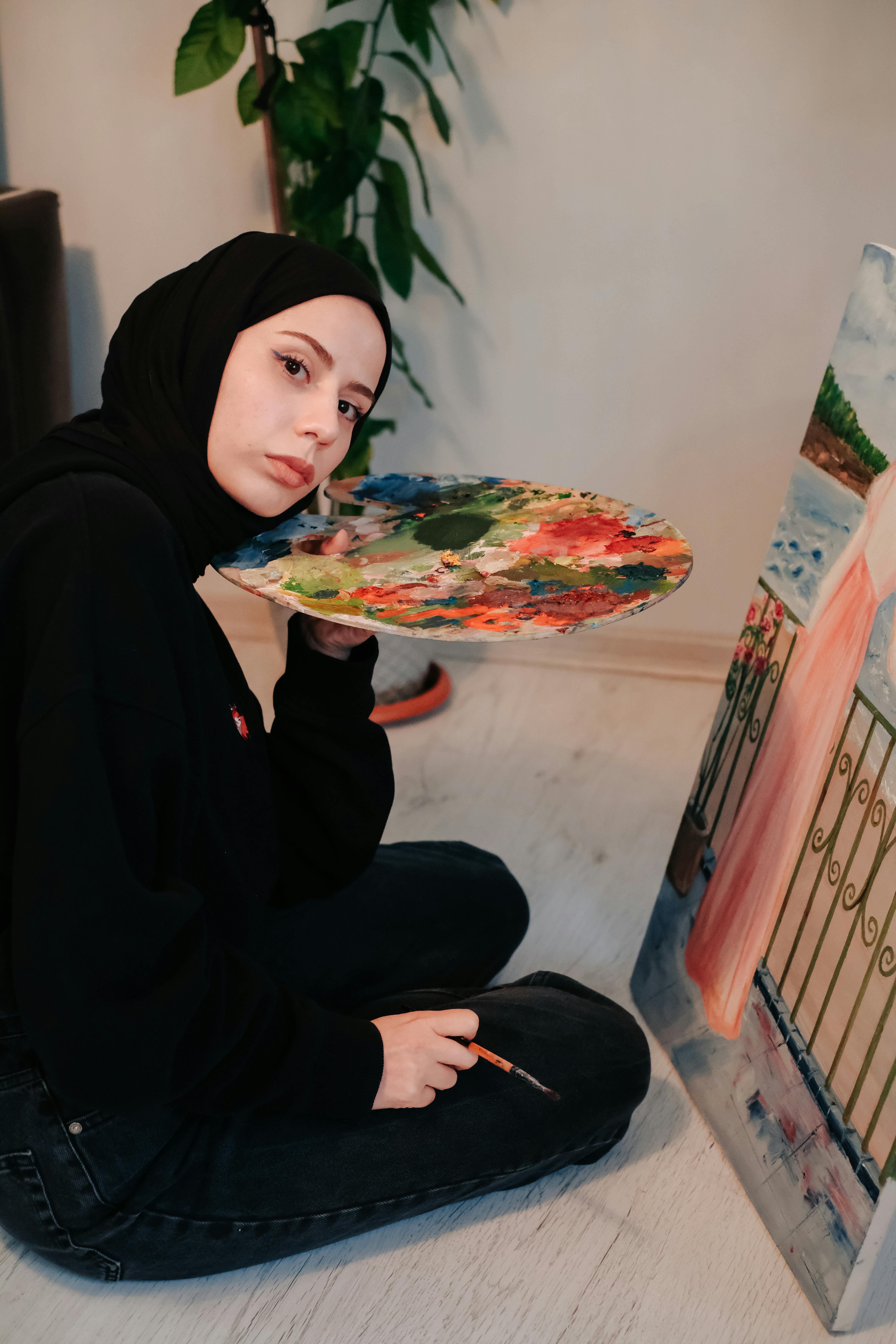 Young woman artist painting with watercolors on a canvas indoors.