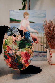 Colorful artist's palette and painting in a cozy studio setting, showcasing creativity.