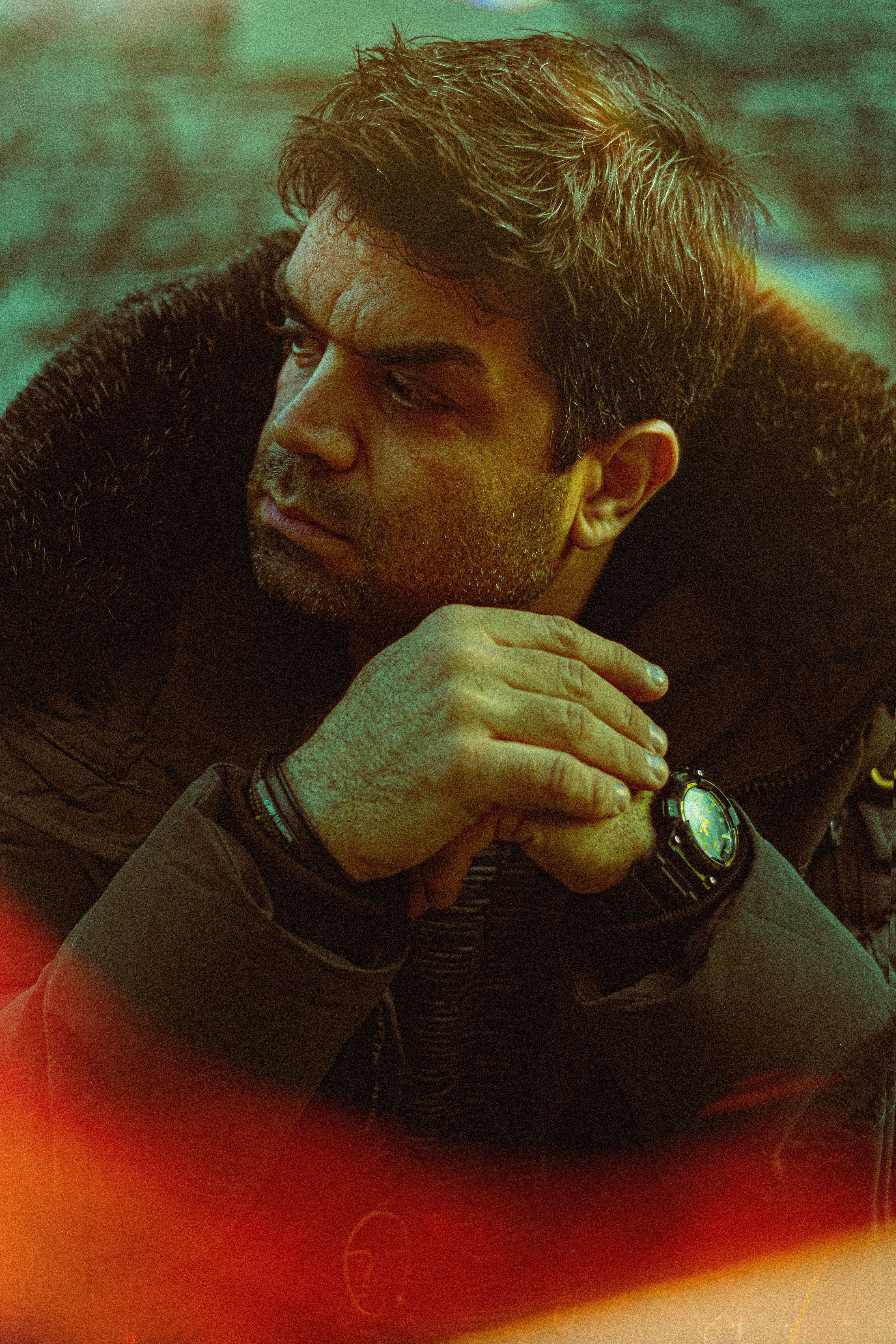 Portrait of a man in winter clothing, sitting pensively, wearing an analog watch.