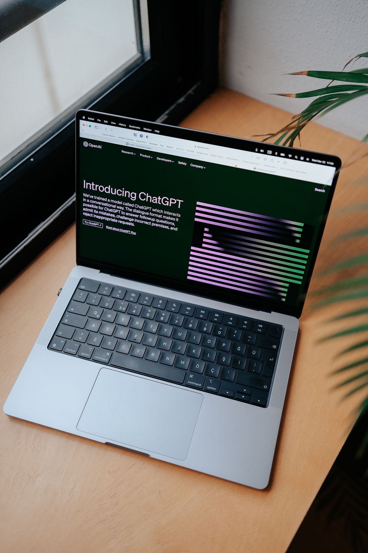 A real laptop displaying the ChatGPT website beside a window