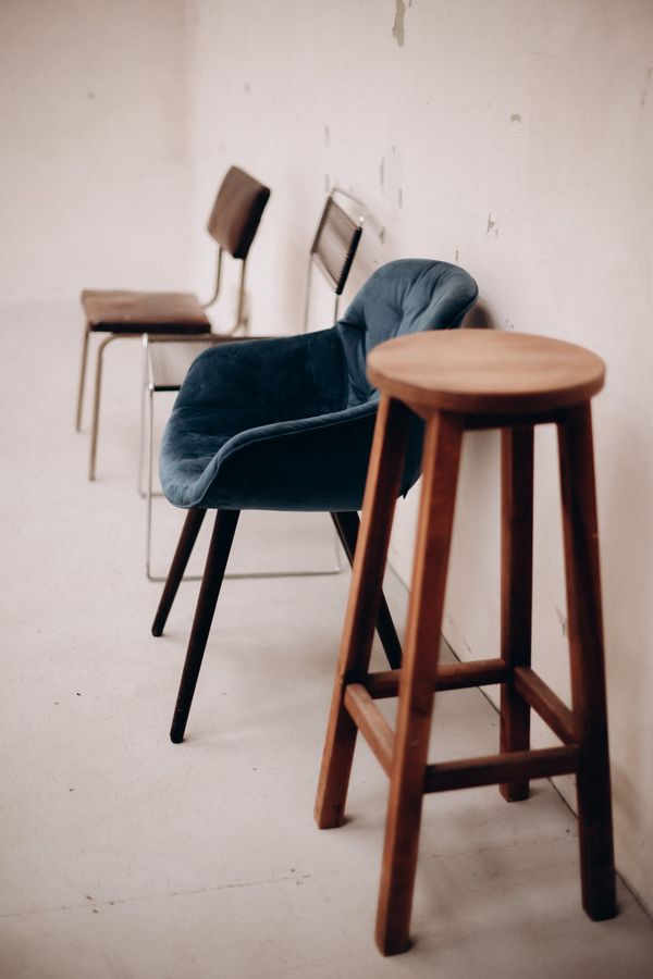 A wooden stool and chairs in an empty room — photo by Alina Komarevska on Pexels