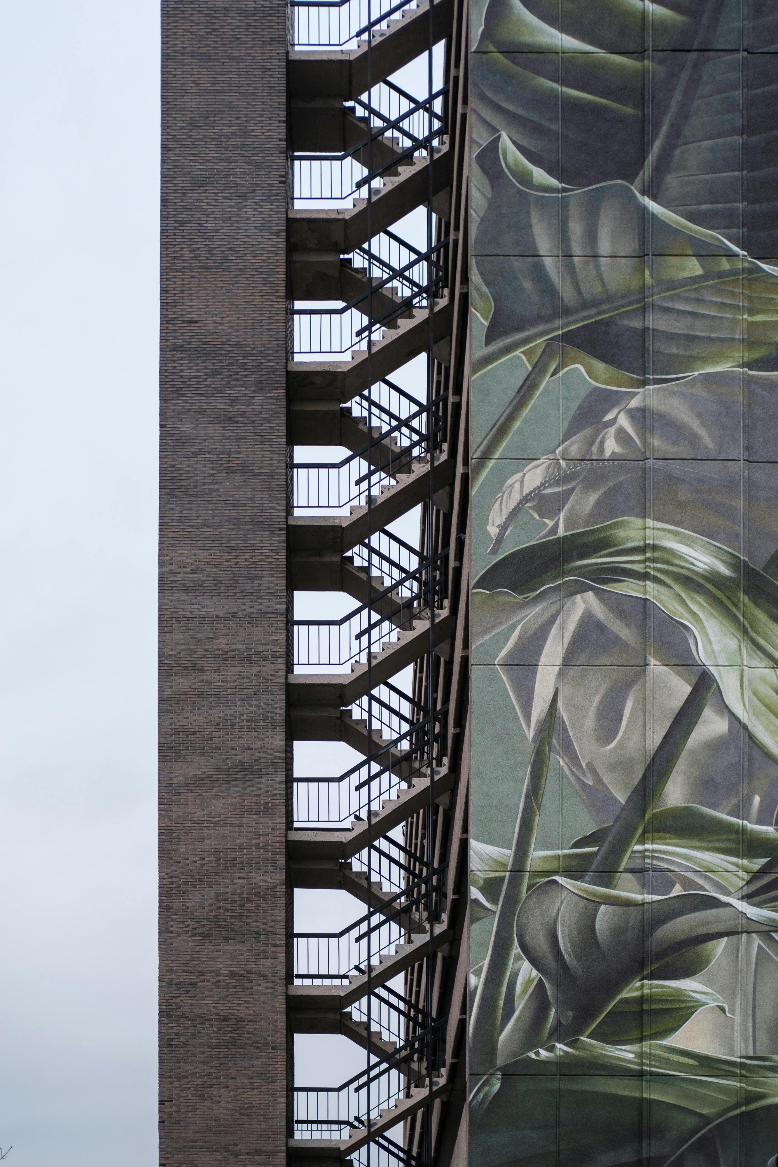 A modern building facade with an artistic mural and adjacent external staircase.