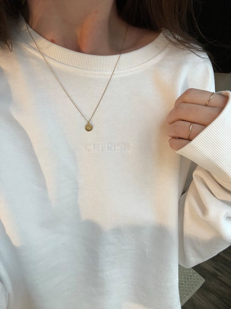 Woman In White Sweatshirt With Rings On Fingers Of Hand