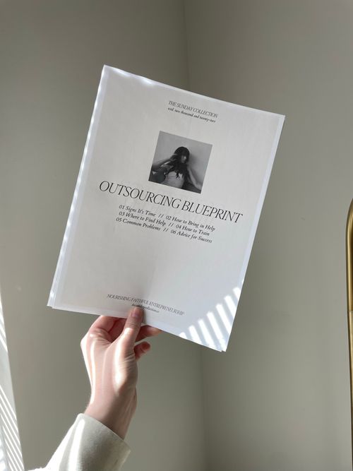 Free A hand holds a printed document titled 'Outsourcing Blueprint' in a sunlit room. Stock Photo
