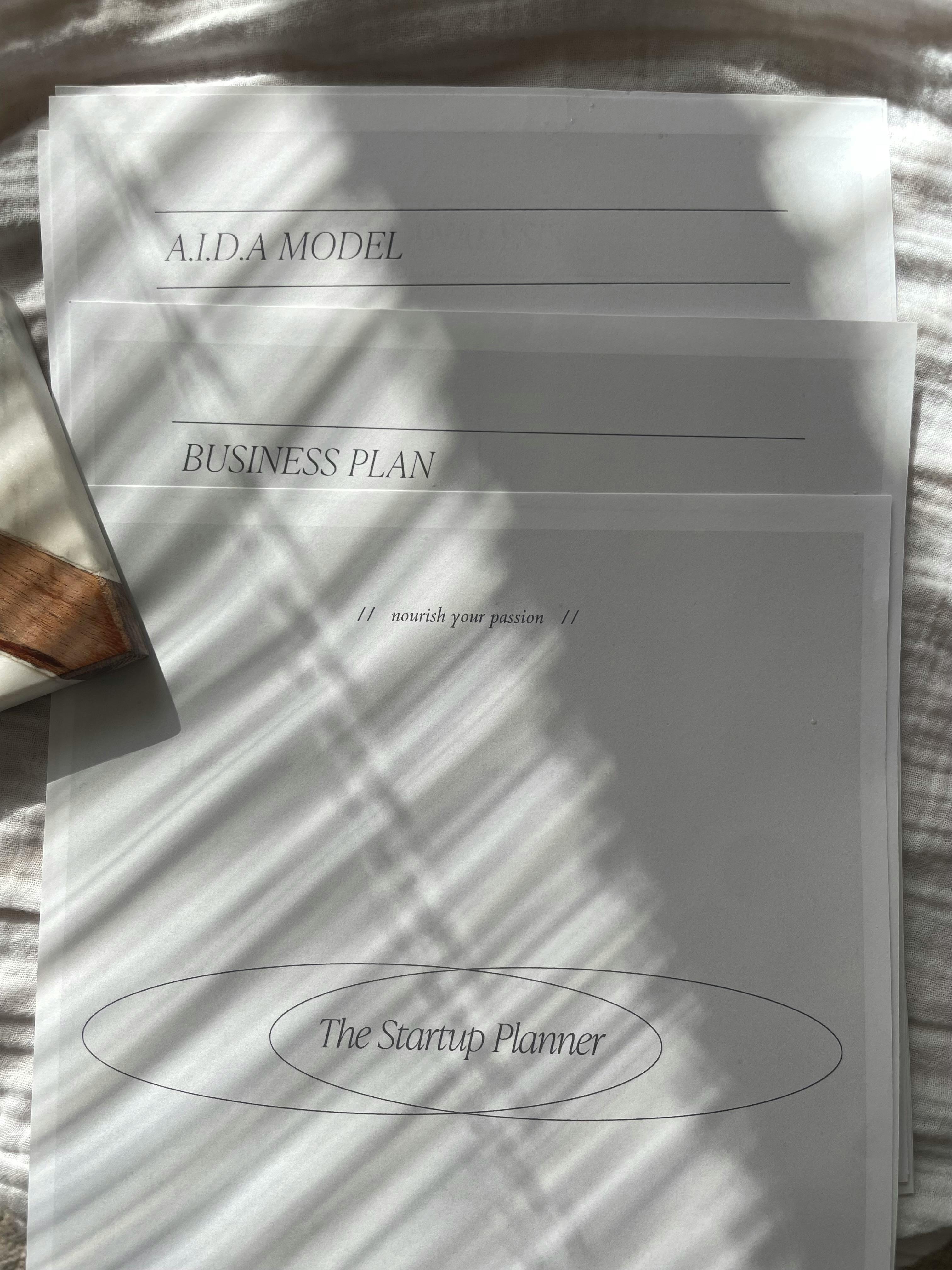 Free A stack of business documents with sunlit shadows, featuring a startup planner. Stock Photo