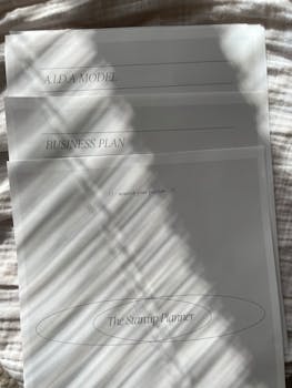 A sunlit set of business plan and AIDA model documents with shadows and copy space.