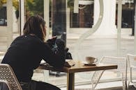 一个女人喜欢在舒适的咖啡桌旁边喝咖啡边用智能手机