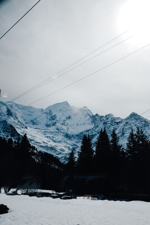 Free Breathtaking view of snow-covered mountains and trees under a bright sky, perfect for winter scenery enthusiasts. Stock Photo