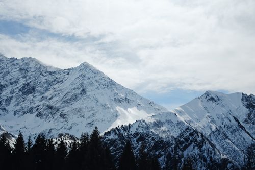 Free Breathtaking view of snow-covered mountains under a partly cloudy sky, capturing winter's serene beauty. Stock Photo