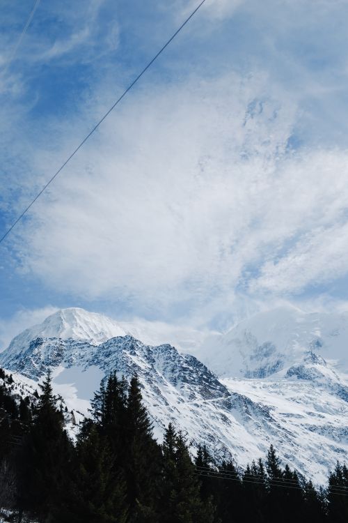 Free A stunning winter scene featuring snow-capped mountains and pine forests under clear blue skies. Stock Photo