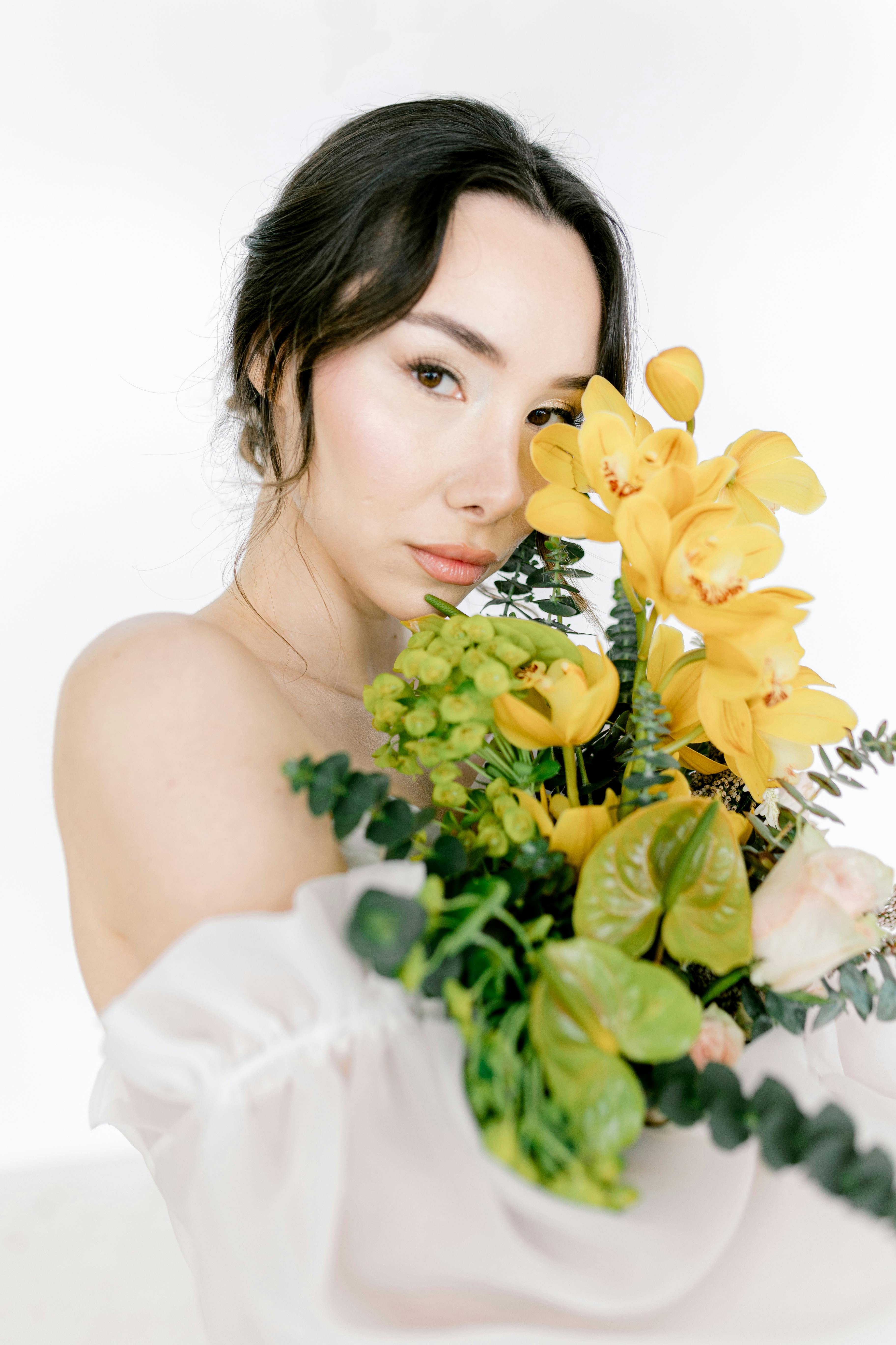 Portrait of a woman with elegant bouquet of yellow orchids in a studio setting.