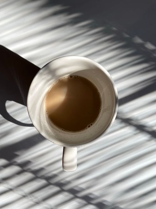 Free A cup of coffee casting shadows in a sunlit room, viewed from above. Stock Photo