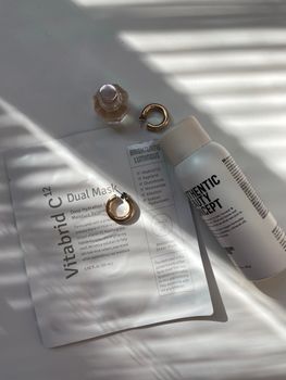 Aesthetic skincare products and jewelry on a softly lit surface, perfect for a modern lifestyle setting.