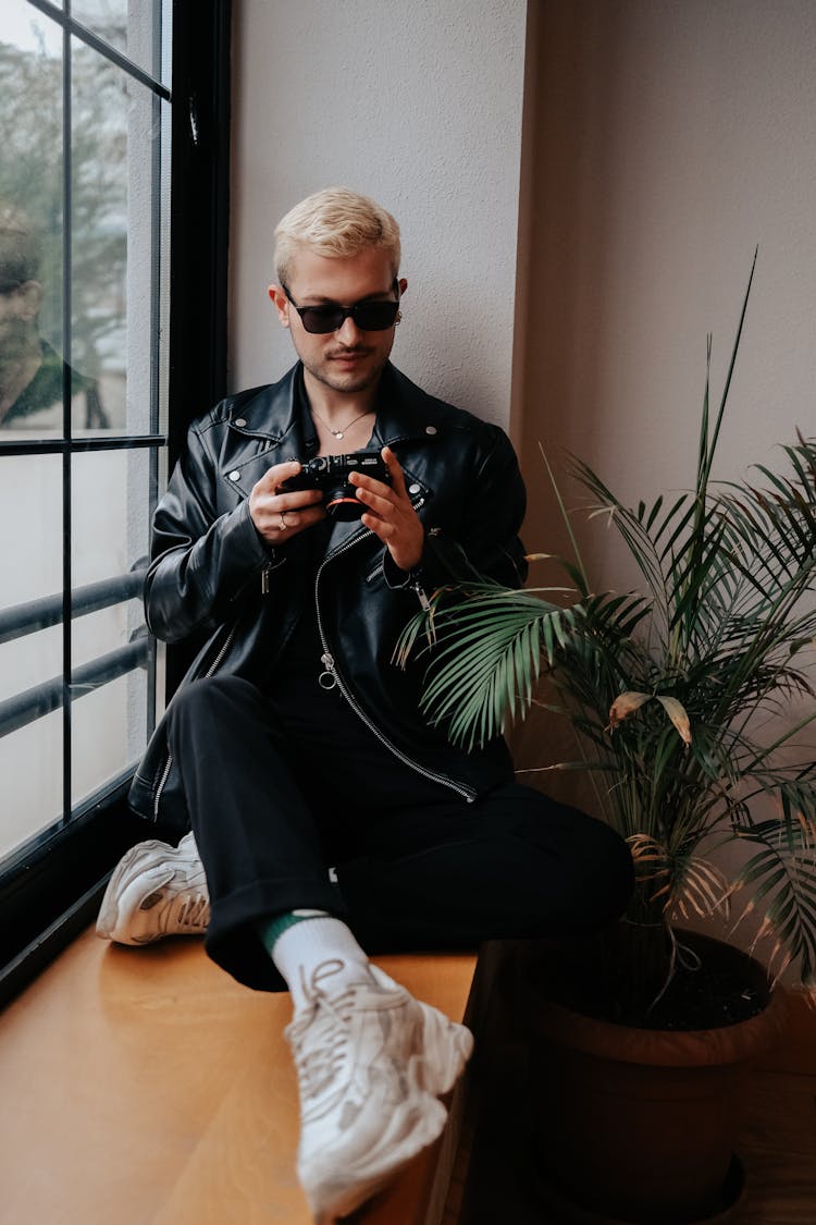 Man Sitting On Windowsill Using Camera