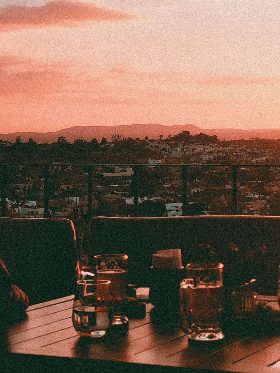 Rooftop terrace with drinks overlooking a city at warm sunset — the elevated dining and social scene that defines Casco Viejo's evenings.