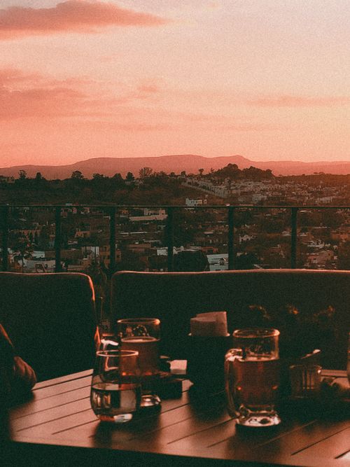 Free Capture the vibrant sunset over San Miguel de Allende from a rooftop terrace with drinks. Stock Photo