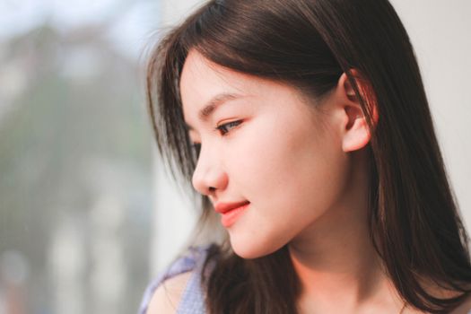 Elegant profile portrait of a smiling woman with long brown hair, captured indoors with natural lighting.