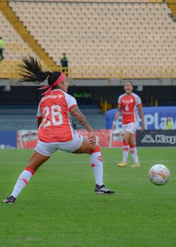 Two women soccer players in action during a competitive football match at a stadium.