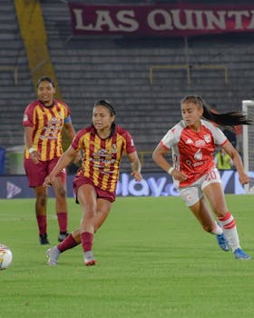 Women playing an intense soccer match under stadium lights.