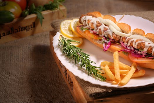 A mouthwatering sandwich with fries and fresh rosemary on a white plate, perfect for lunch or dinner.