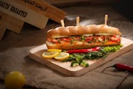 木板上摆着令人垂涎的三明治、蔬菜和香肠，非常适合作为美味的一餐