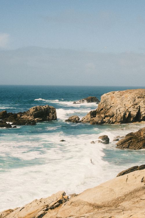 Free Dramatic view of waves crashing against rugged rocks on a clear day. Stock Photo