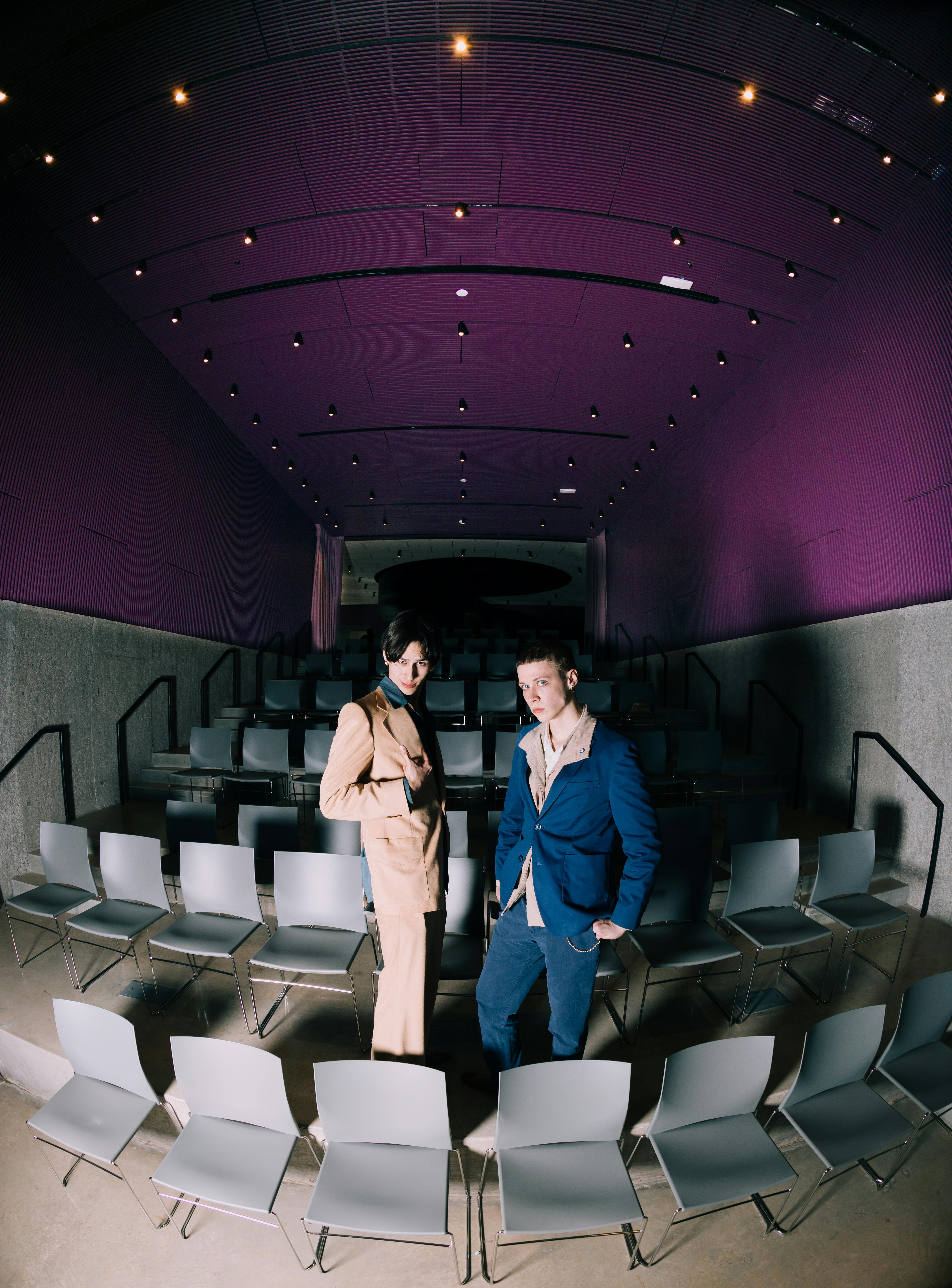 Free Stylish individuals posing in a modern auditorium with purple accents. Stock Photo