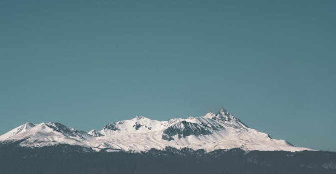 在晴朗的蓝天下欣赏白雪皑皑的山峰，是冬季旅行的绝佳灵感来源