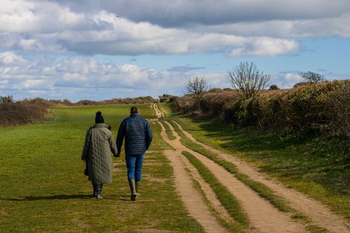 Free Couple holding hands, walking on a scenic path in Bournemouth, England. Stock Photo