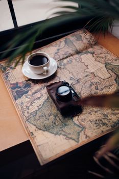 A vintage camera and coffee cup on an old map create a nostalgic travel vibe.