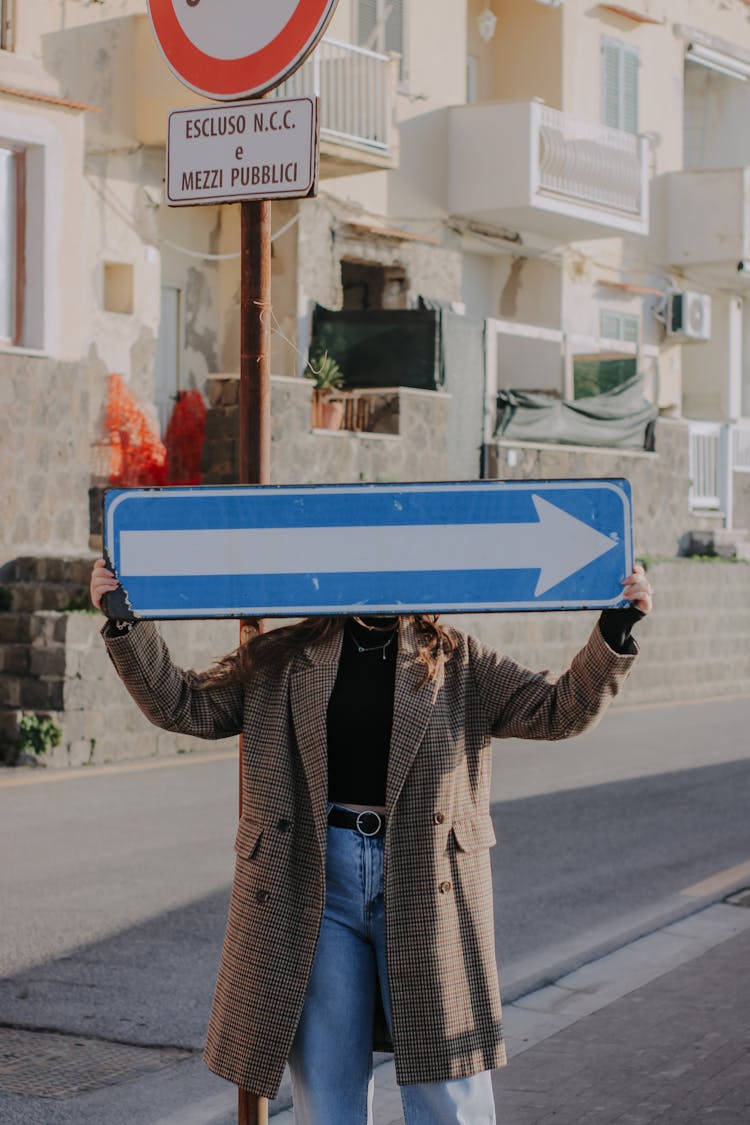 Portrait Of Woman Holding Directional Sign