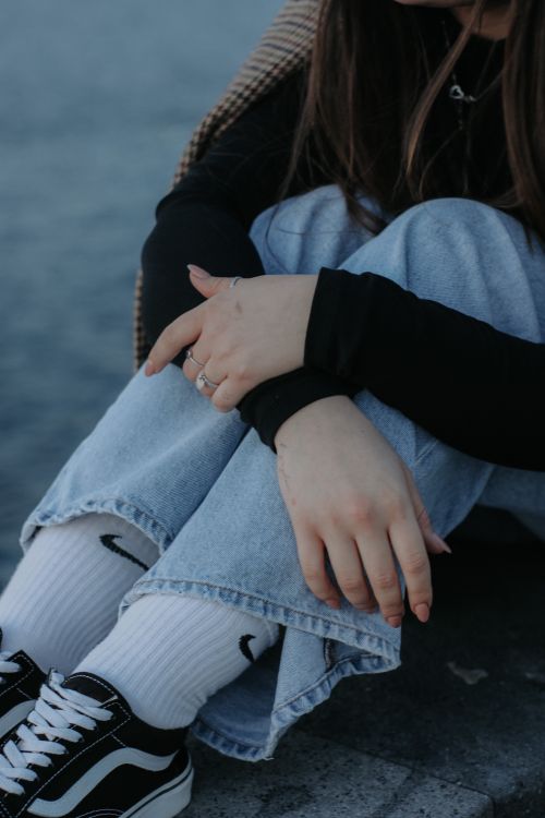 Free Close-up portrait of a woman in casual fashion showing jeans and sneakers with a relaxed pose. Stock Photo