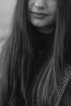 Close-up black and white portrait of a young woman smiling with long hair and sweater.