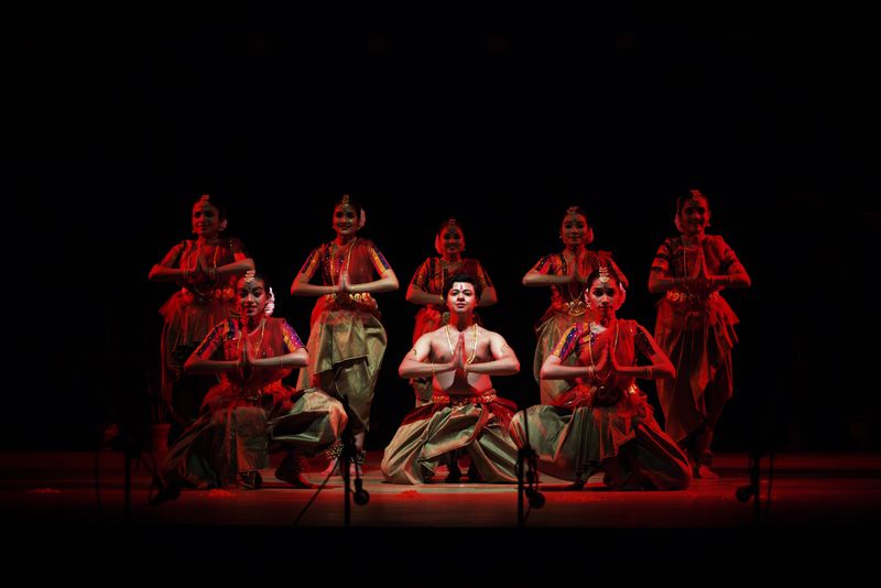 Dancers performing on stage under dramatic red lighting