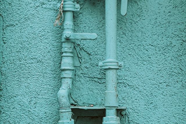 Natural gas meter on a house wall Gas meter and pipes painted to match the color of a house