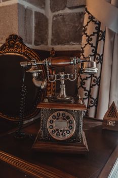 Close-up of an ornate vintage rotary telephone on a wooden desk in a classic room.