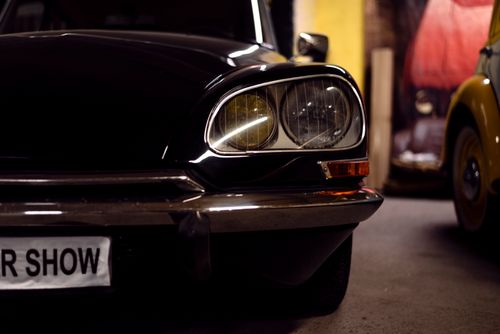 Free Detailed view of a classic black car's headlight at an indoor auto show. Stock Photo