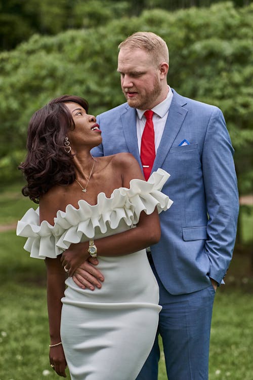 Bride and Groom Standing in a Park, Embracing and Looking at Each Other 