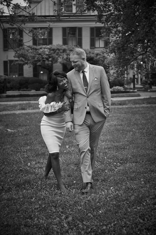 Black and White Photo of Bride and Groom Walking Outside and Smiling 