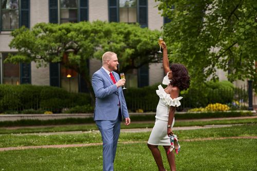 Free An elegant couple celebrates in a garden with champagne, dressed for a special occasion. Stock Photo