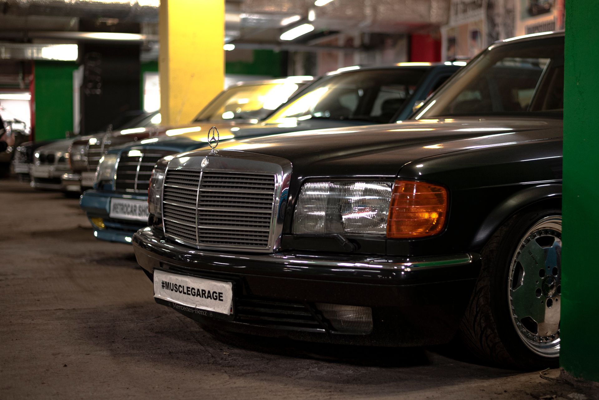 Close-up of vintage Mercedes cars lined up in an indoor garage, highlighting classic design.