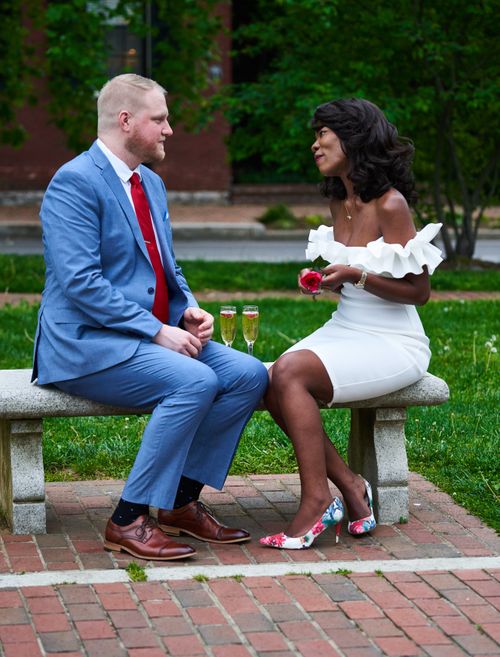 Free Engaged couple in stylish attire sitting on a park bench with champagne glasses. Stock Photo