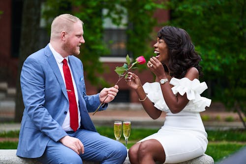 Photo of a Couple Celebrating Engagement with a Rose and Champagne