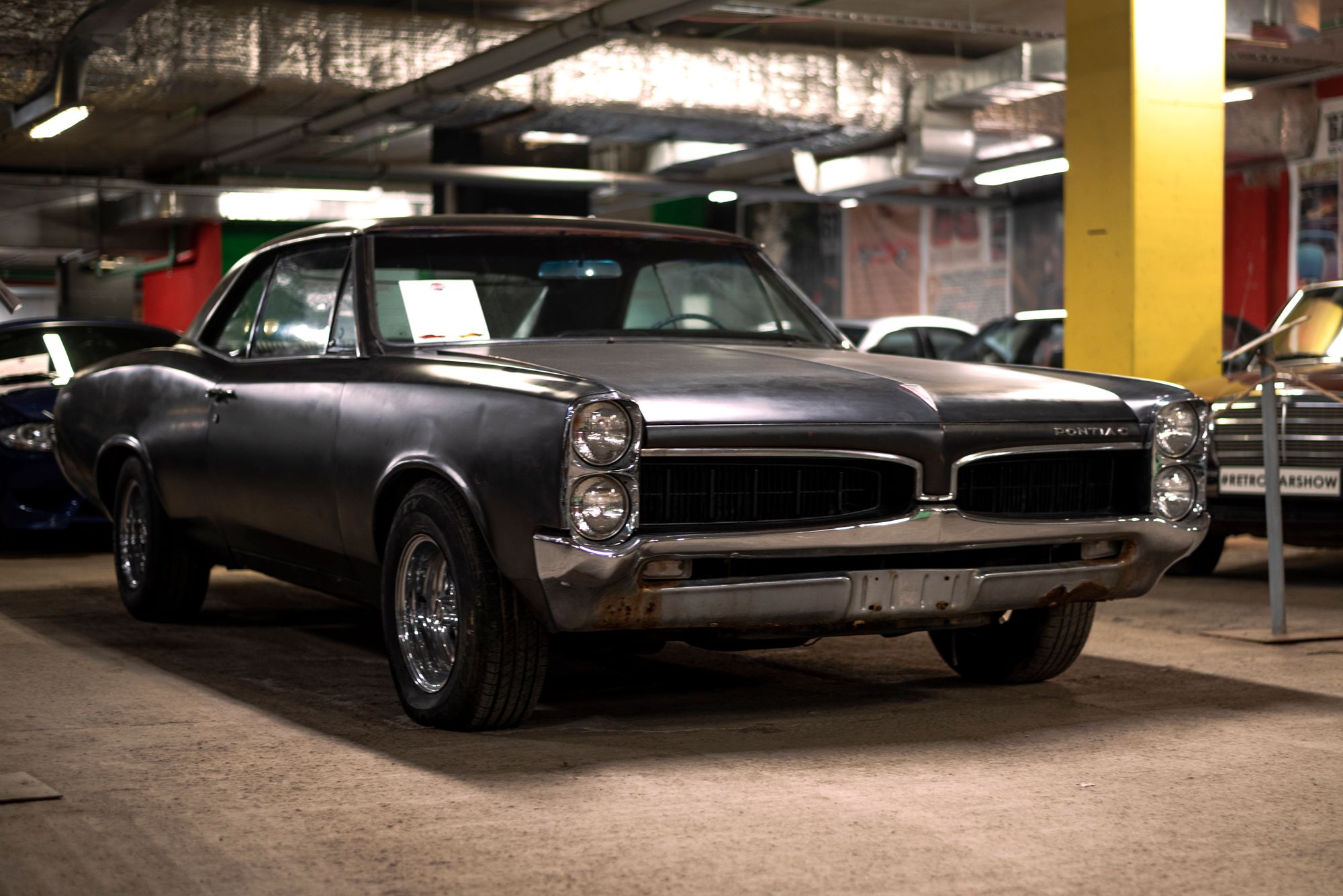 A vintage Pontiac muscle car in an indoor garage directly illustrates the muscle car buyer segment discussed in this section.