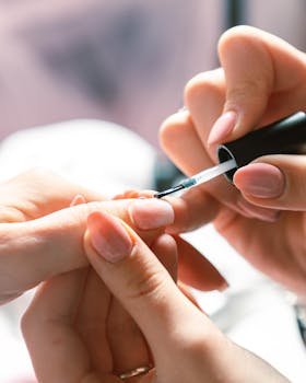 Detailed view of a woman's hands receiving a manicure at a nail salon, highlighting precision.