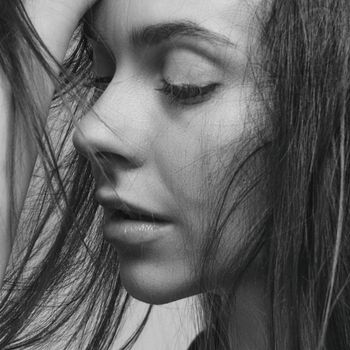 Close-up black and white portrait of a woman with eyes closed, conveying deep emotion.