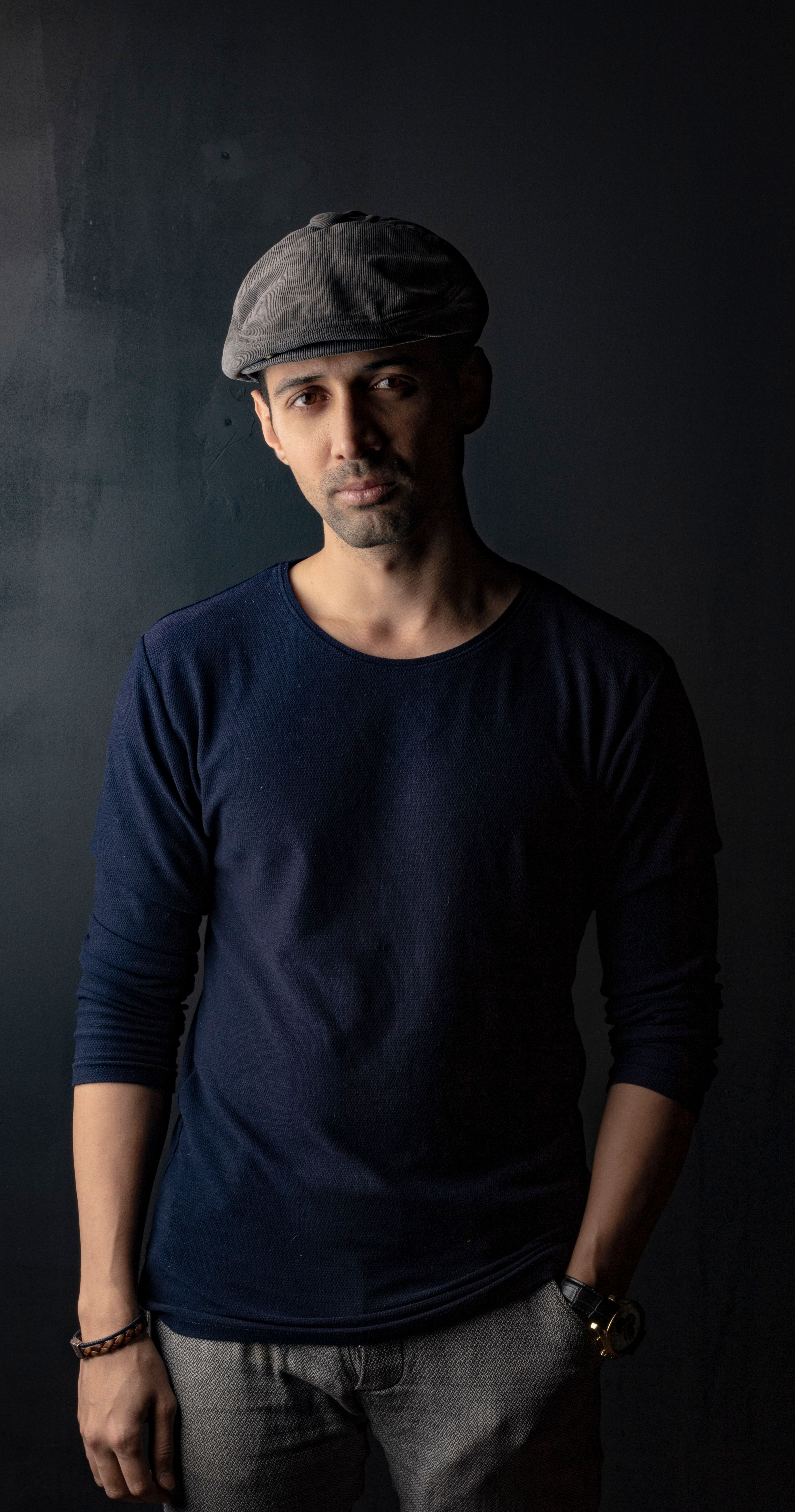 Stylish portrait of a man wearing casual clothing and a flat cap, posing confidently.