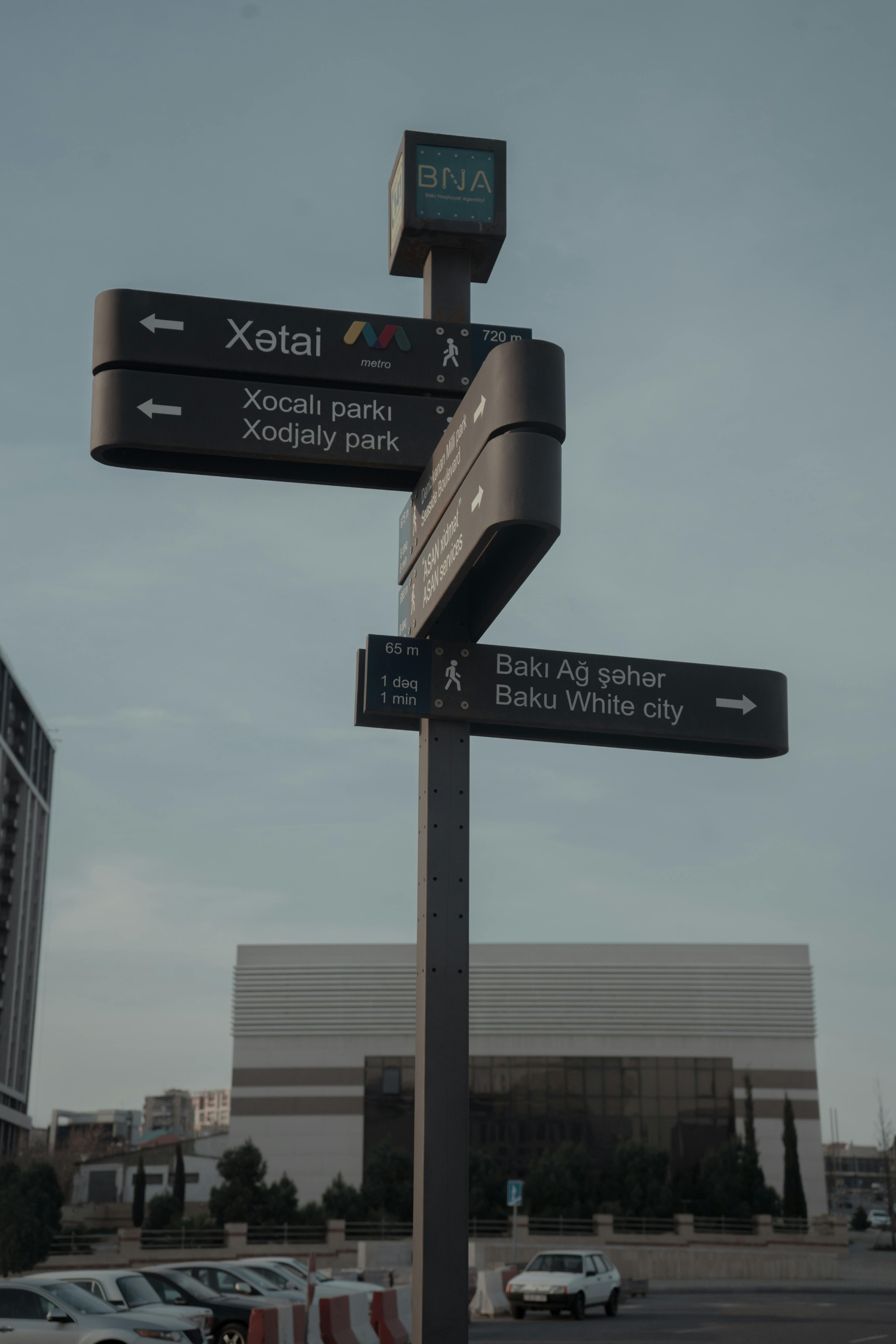 Urban street sign in Baku, Azerbaijan against modern architecture, highlighting directional guidance.