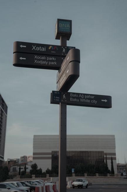 Urban street sign in Baku, Azerbaijan against modern architecture, highlighting directional guidance.