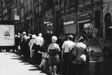 A line of people waiting outside a restaurant during lunch rush.